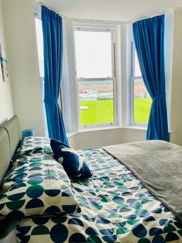 a bedroom with a bed with blue curtains and a window at Keepers Rest Apartment - Scarborough in Scarborough