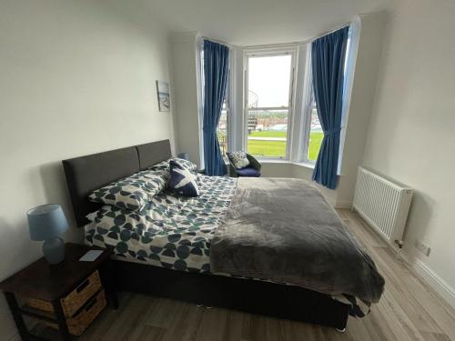 a bedroom with a bed and a window with blue curtains at Keepers Rest Apartment - Scarborough in Scarborough