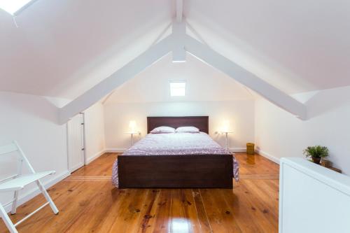 a bedroom with a bed in a white attic at Apartment Junqueiro in Porto