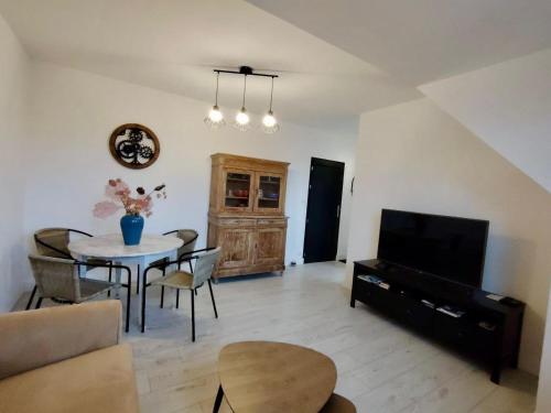 un salon avec une table et une télévision dans l'établissement Résidence le Parc, à Saint-Pierre-du-Regard