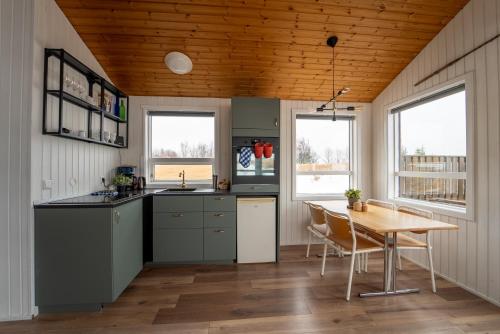 a kitchen with a table and a wooden ceiling at Smáratún Cottages & Chalets in Hellisholar