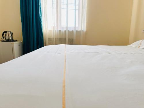 a white bed in a room with a window at SD Hotel in Yerevan