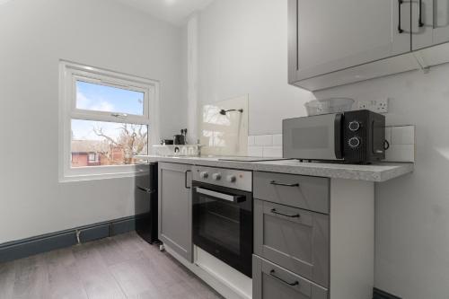 a white kitchen with a microwave and a stove at Luxury Moseley Studio - 8 in Birmingham