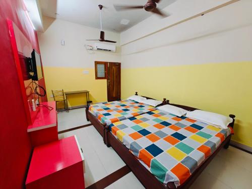 a bedroom with a colorful bed and a chair at SAlBALA LODGE - AC ROOMS WITH COOKING FACILITIES Near CMC in Vellore