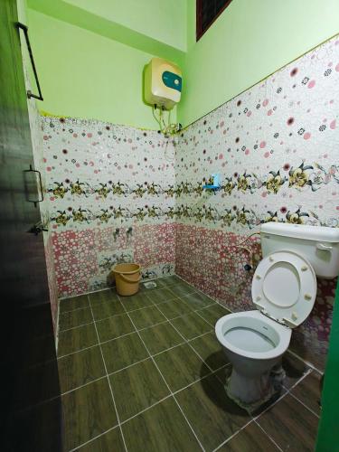 a bathroom with a toilet and flowers on the wall at SAlBALA LODGE - AC ROOMS WITH COOKING FACILITIES Near CMC in Vellore