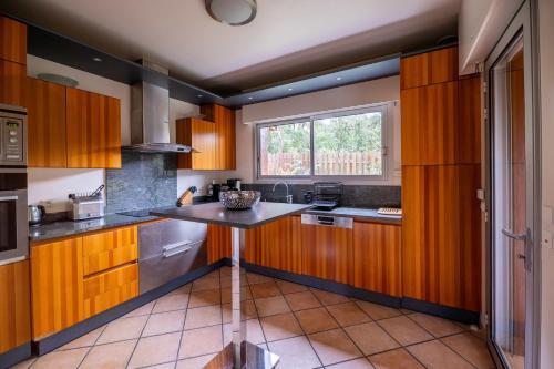 una cucina con mobili in legno e un tavolo al suo interno di Villa Doña Sol a La Teste-de-Buch