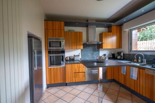 une cuisine avec des armoires en bois et des appareils en acier inoxydable dans l'établissement Villa Doña Sol, à La Teste-de-Buch