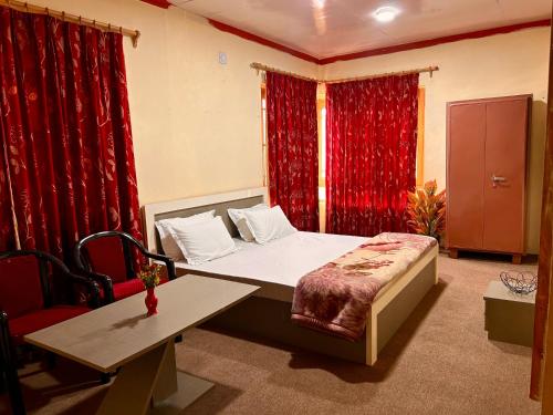 a room with a bed and a table and red curtains at Kashmiri kothi - Srinagar stay in Srinagar