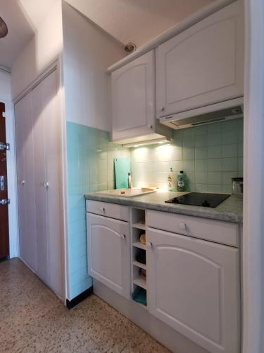 une cuisine avec des armoires blanches et un évier dans l'établissement Studio - 2 double lits, clim, au calm, près du lac, golf, à La Grande Motte