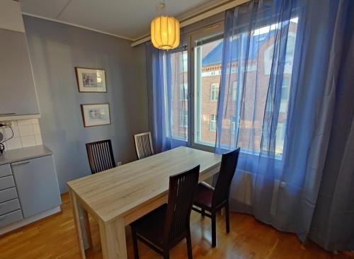 a dining room table with chairs and a large window at Style in Center by AinaBnB in Vaasa