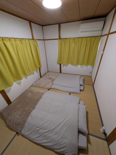two beds in a small room with yellow curtains at Villa Hachiman-bori ヴィラ八幡堀 in Omihachiman