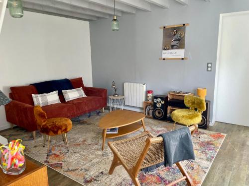a living room with a red couch and chairs at Longère cœur de village proche des plages in Sassetot-le-Mauconduit
