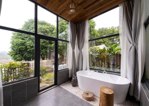 a bathroom with a large tub and large windows at Yingde YeDuGu Resort in Gaozhoupu