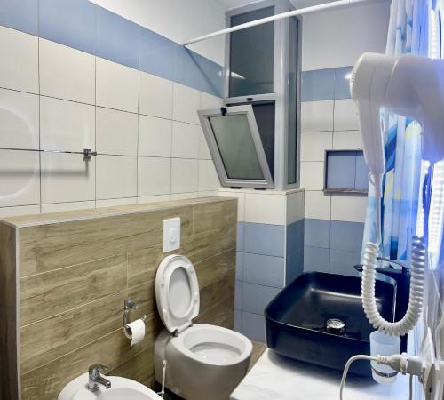 a bathroom with a toilet and a tv on the wall at Beach Apartments Durres in Durrës