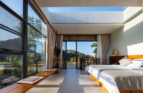 a bedroom with a bed and a large window at Yingde YeDuGu Resort in Gaozhoupu