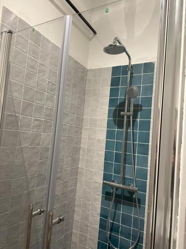 La salle de bains est pourvue d'une douche et de carrelage bleu. dans l'établissement Ancien musée de la noix, à Doissat