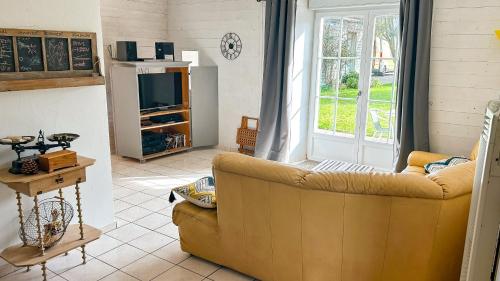 un salon avec un canapé et une télévision dans l'établissement Grande maison traditionnelle Rhétaise ancienne, à La Couarde-sur-Mer