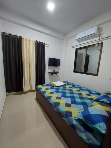 a bedroom with a bed with a checkered blanket at Palm Villa and Cottage in Alibaug