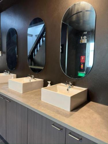 a bathroom with two sinks and two mirrors at Hood Pattaya in Pattaya
