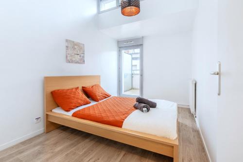 a bedroom with a bed with orange pillows and a window at Triplex cosy à 20min des Champs Elysées in Gennevilliers
