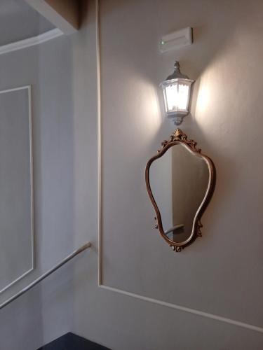 a mirror on a wall with a light on it at Hotel Tourist House in Florence