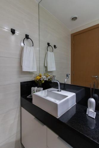 a bathroom with a white sink and a black counter at Sweet Studio - GRU 19º in Guarulhos