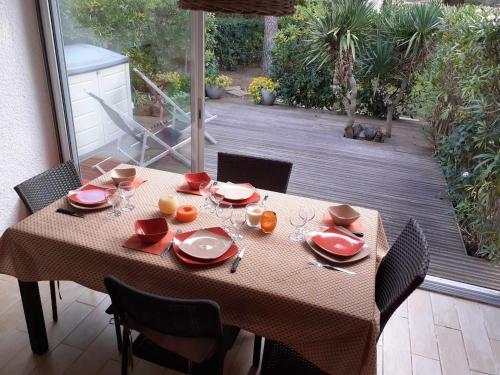 une table avec des assiettes rouges et des verres sur une terrasse dans l'établissement cap houra, au Cap d'Agde