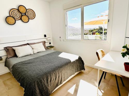a bedroom with a bed and a desk and a window at Villa Margarita ocean view and private heated pool in Adeje