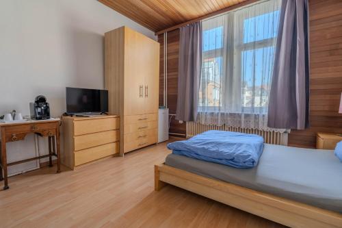 a bedroom with a bed and a tv and a window at Pension Bärbel Neelen in Hameln