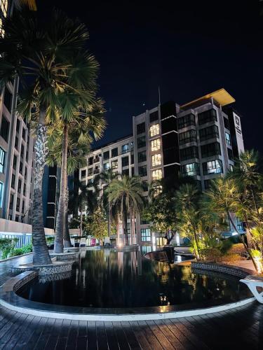 a large pool with palm trees in front of a building at The private paradise 2 in Pattaya North