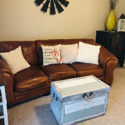 a brown leather couch with pillows and a box at Athens in Style! in Athens