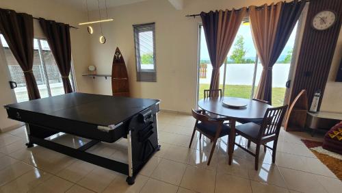 ein Esszimmer mit einer Tischtennisplatte und einem Tisch und Stühlen in der Unterkunft Villa 63 3Bedroom 8pax in Beranang