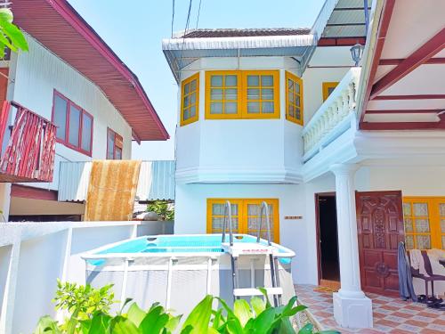 a white house with yellow windows and a porch at Retreat House 81 - BTS Onnut in Bangkok