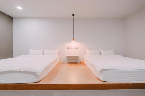 two beds in a white room with a pendant light at 又一天 Koh Tsit Kang in Suao