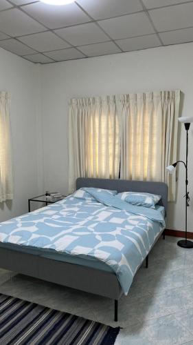 a bedroom with a bed with blue sheets and windows at BB Sweet Home in Ban Hin Kong (1)