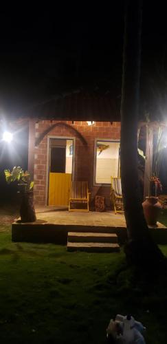 a house with a yellow door at night at FAZENDA BOSQUE DAs PALMEIRAS in Itamaracá