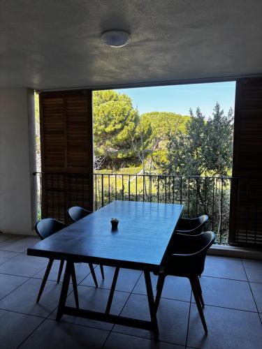 une table et des chaises dans une pièce avec une grande fenêtre dans l'établissement Appartement AMBRE T2 a 100 Métres de la Mer, à Saint-Florent