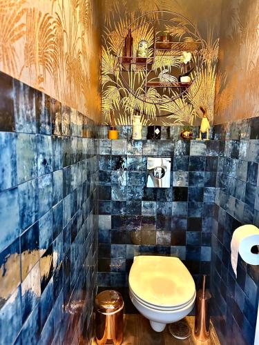 La salle de bains est pourvue de toilettes et d'un mur carrelé bleu. dans l'établissement joli T2 situé dans le coeur de Cabourg, à Cabourg