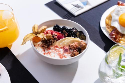a bowl of cereal and fruit on a table with a drink at Icon Suites by the sea in Potos