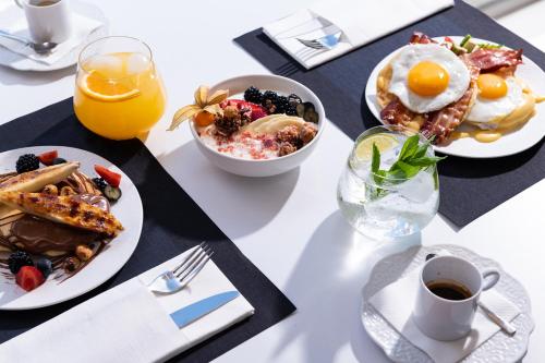 a table with plates of breakfast food and a glass of orange juice at Icon Suites by the sea in Potos