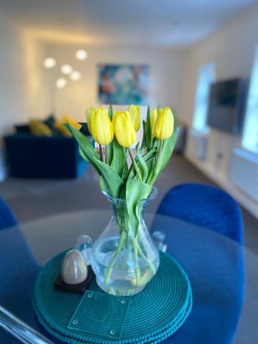 a vase filled with yellow flowers on a table at The Apartment, Bridge House in Laxey