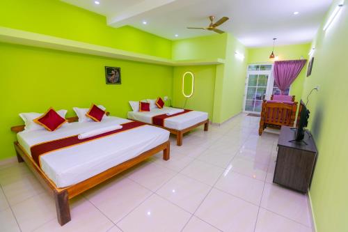 a green room with two beds and a television at Suite Room-Varadha Residency in Kālapettai