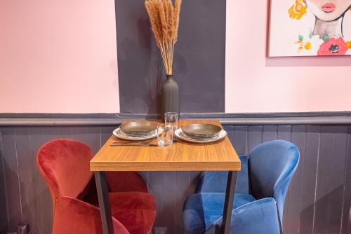 une table en bois avec deux assiettes et un vase dans l'établissement Atypical, Downtown, Fast Wi-Fi - Le Cosy Pop, à Angers