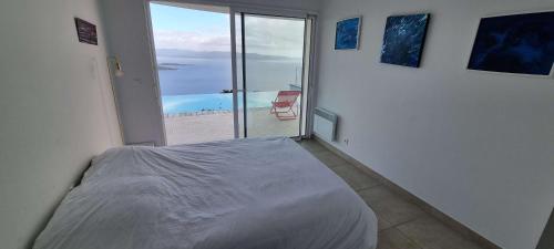 Un dormitorio con una cama y vista al mar. en Villa de standing piscine chauffée vue mer Corse du sud, en Coti-Chiavari