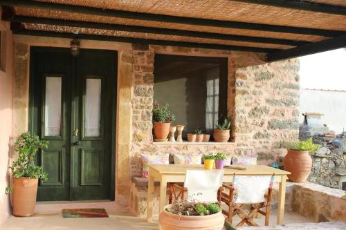 a patio with a green door and a table and chairs at Orgon Farm Traditional Houses in Apóstoloi