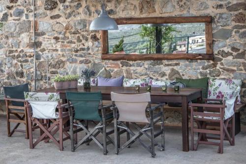 a dining room table and chairs with a stone wall at Orgon Farm Traditional Houses in Apóstoloi