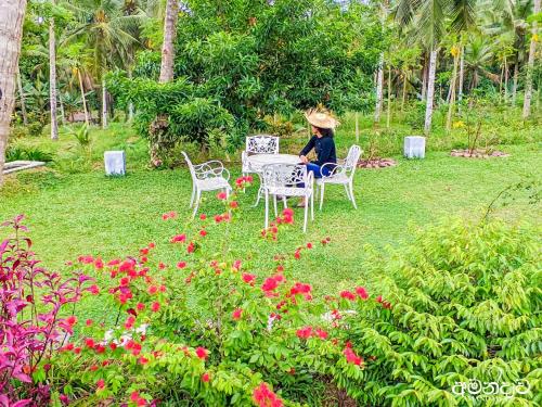 a woman sitting at a table in a garden at Amandawa Eco in Gampaha