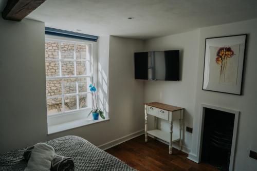 a bedroom with a bed and a television and a window at Rose & Star Cottage in Frome