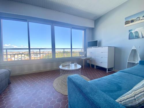 un salon avec un canapé bleu et une table dans l'établissement L'océania Joli studio 3 personnes au pied de la Grande plage, à Saint-Gilles-Croix-de-Vie