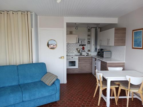 un salon avec un canapé bleu et une cuisine dans l'établissement L'océania Joli studio 3 personnes au pied de la Grande plage, à Saint-Gilles-Croix-de-Vie